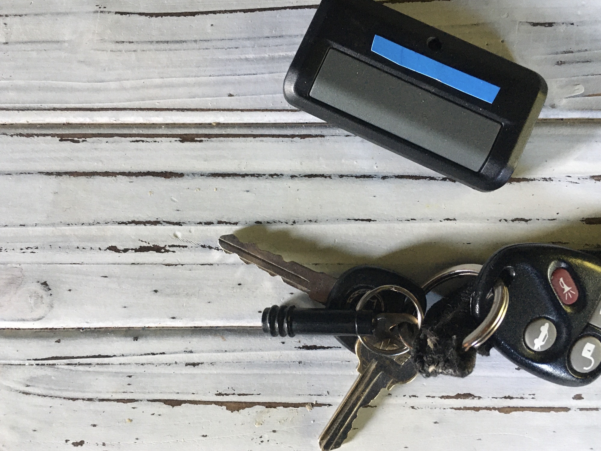 Keys and garage door opener on white background